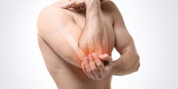 Young man suffering from elbow pain on light background. Health care concept